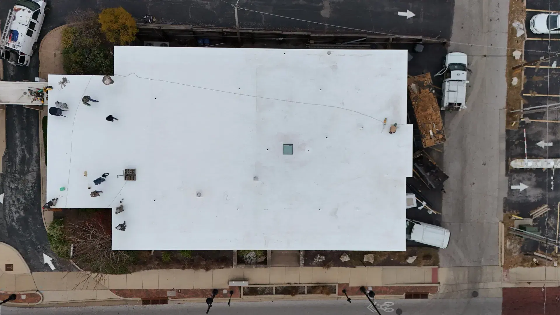 Overhead aerial view of a white flat roof with the crew at work