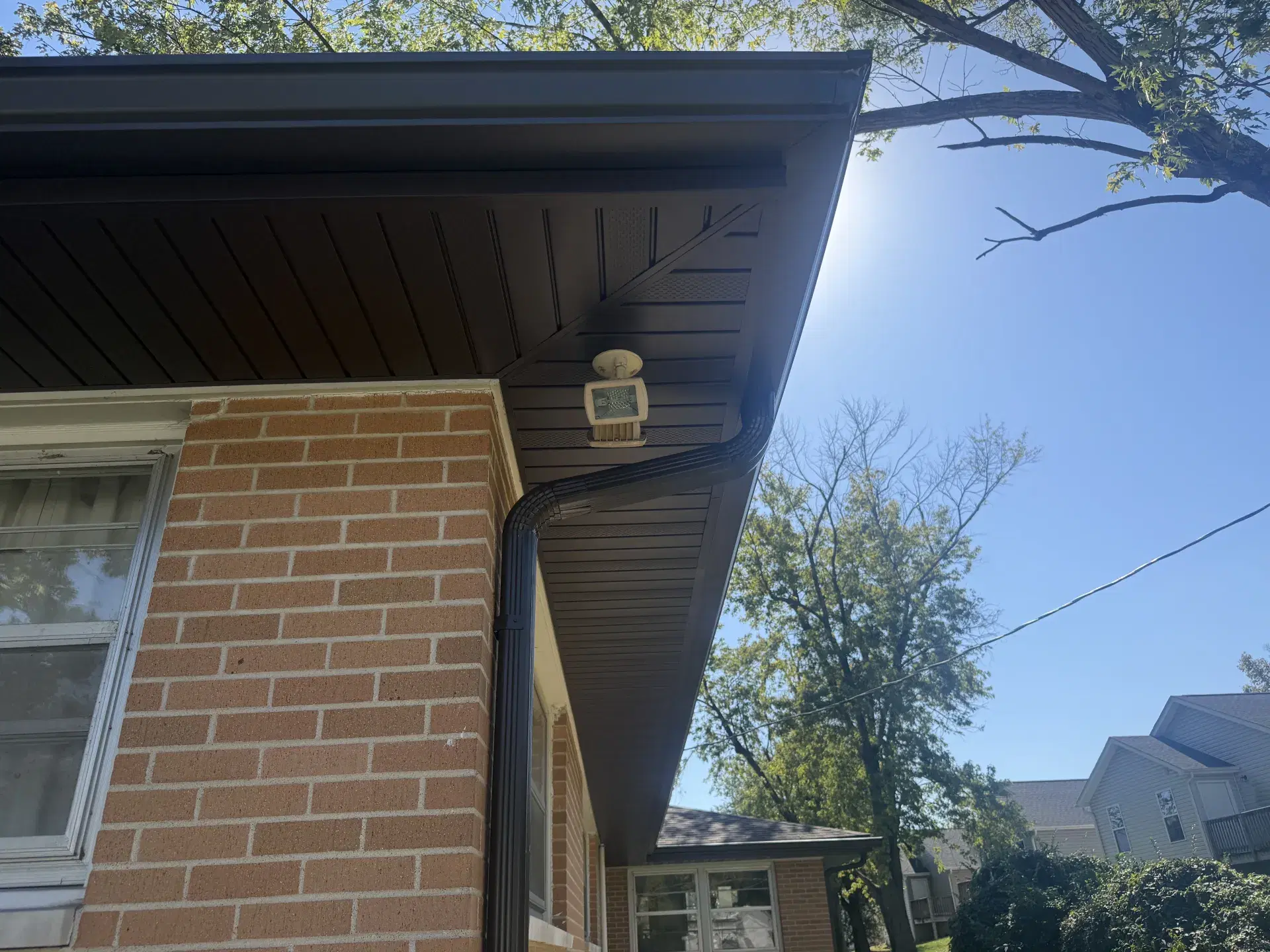 New dark soffit, fascia, gutter, and downspout on a brick home