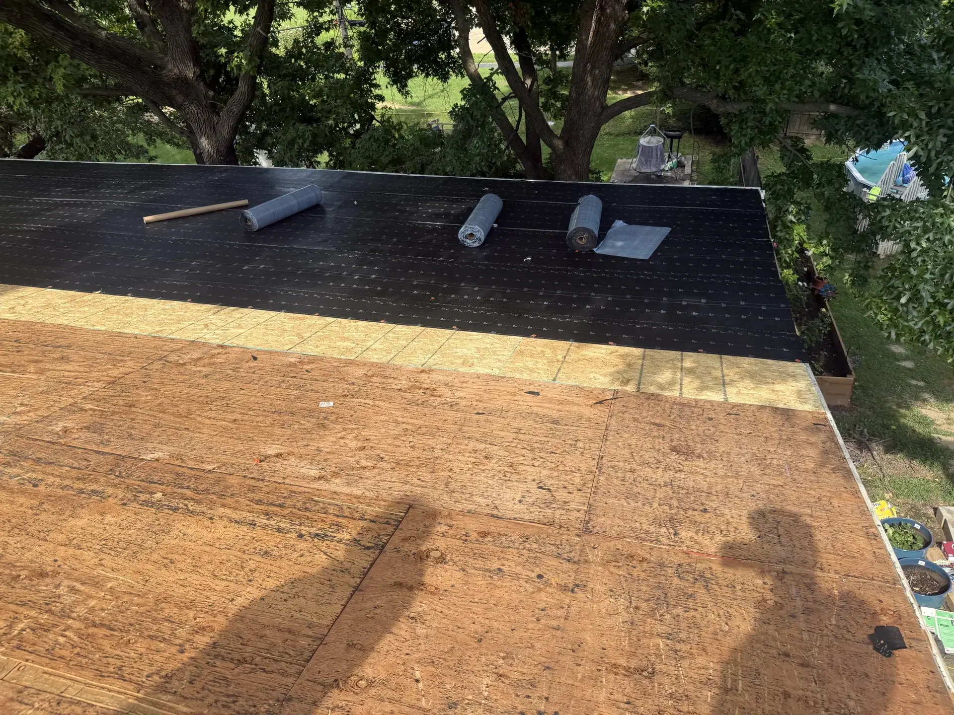 Exposed roof decking alongside a shingle roof during work