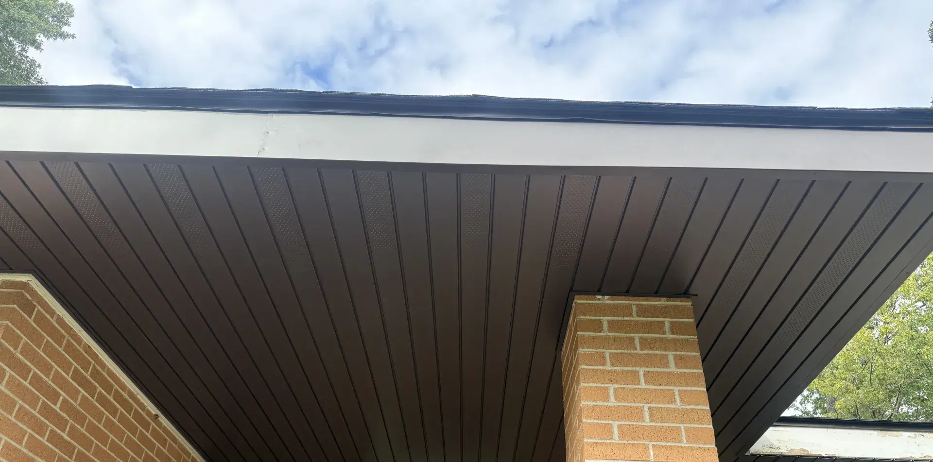 New dark vented soffit and fascia over a brick front porch